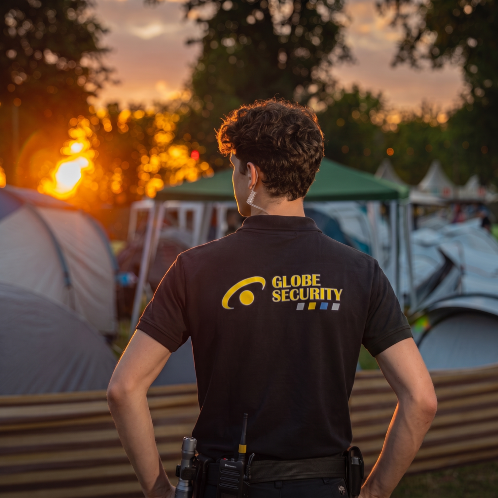 Beveiliger van Globe Security houdt toezicht op een evenemententerrein tijdens zonsondergang.