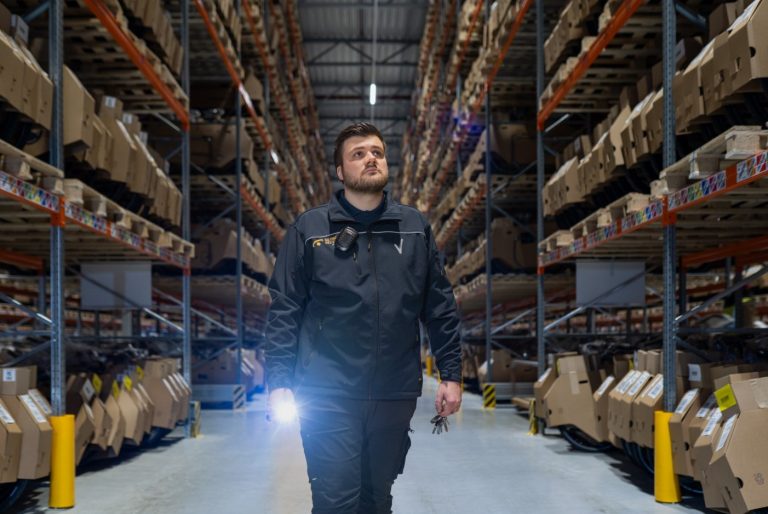 Beveiliger met zaklamp tijdens ronde in magazijn